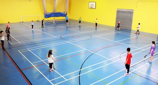 Children playing hockey in a sports hall