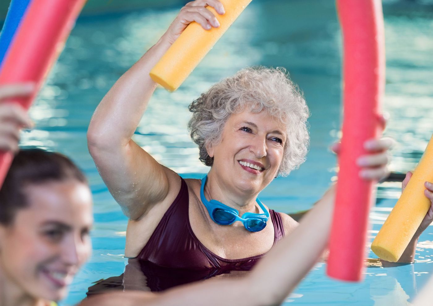 Lady in the pool holding a woggle above her head